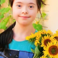 A girl holding sunflowers in her hands.